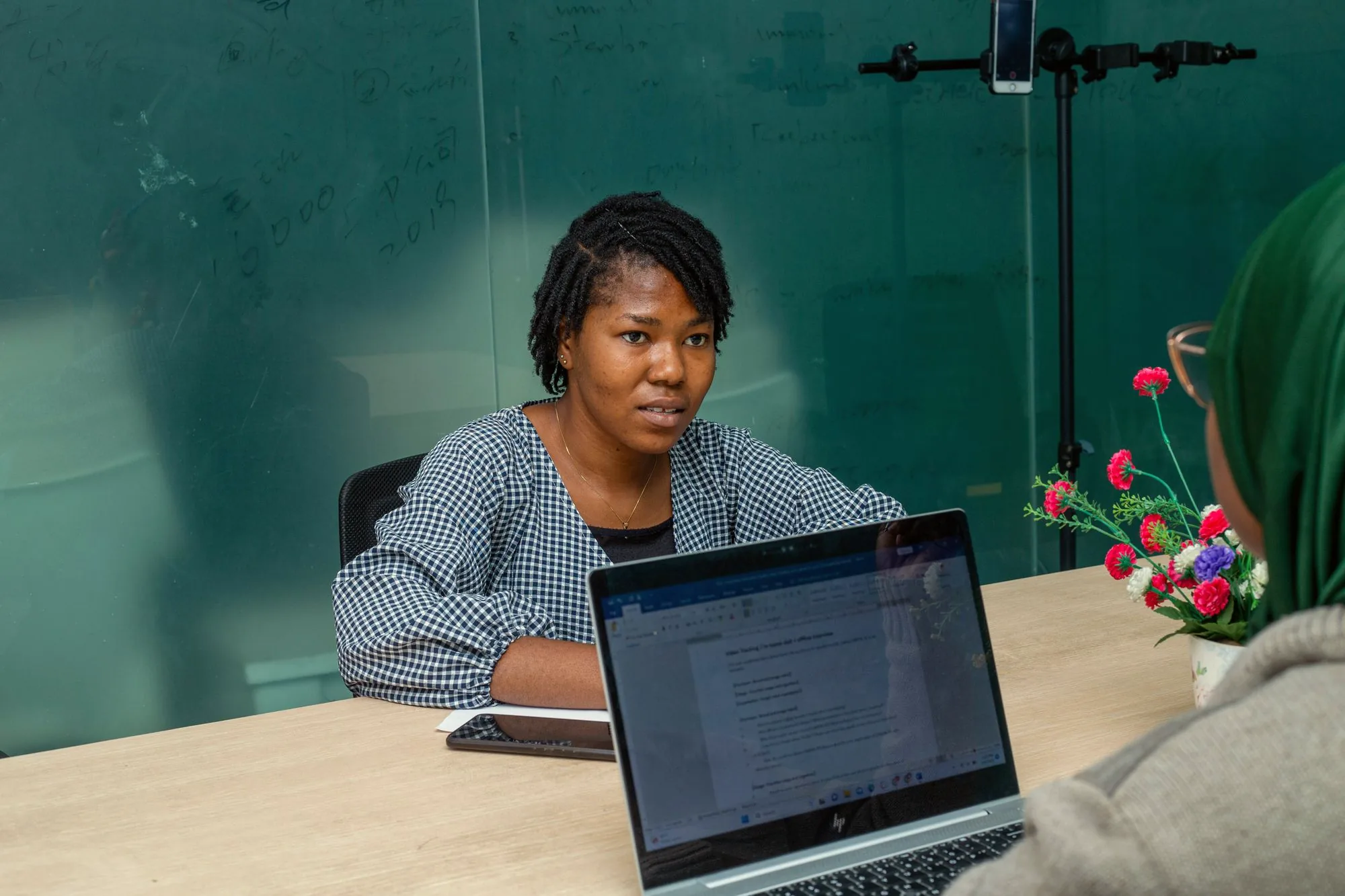 Two women collaborating on laptops in a bright office