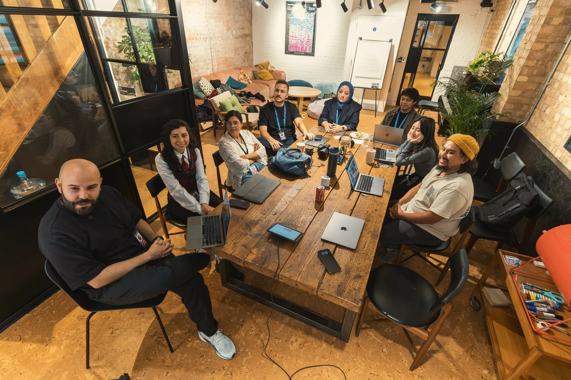 Team collaborating on laptops around a wooden table