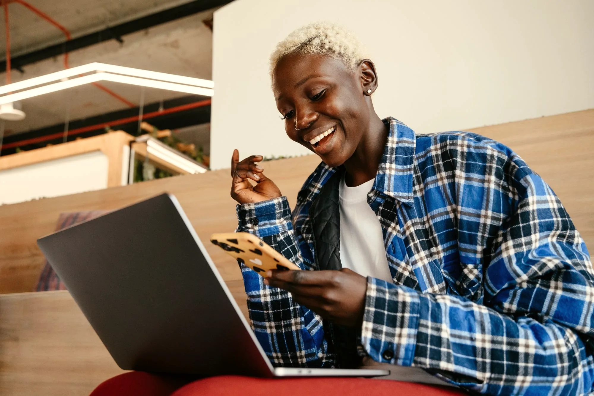 Smiling marketer checking campaign results on a laptop and phone