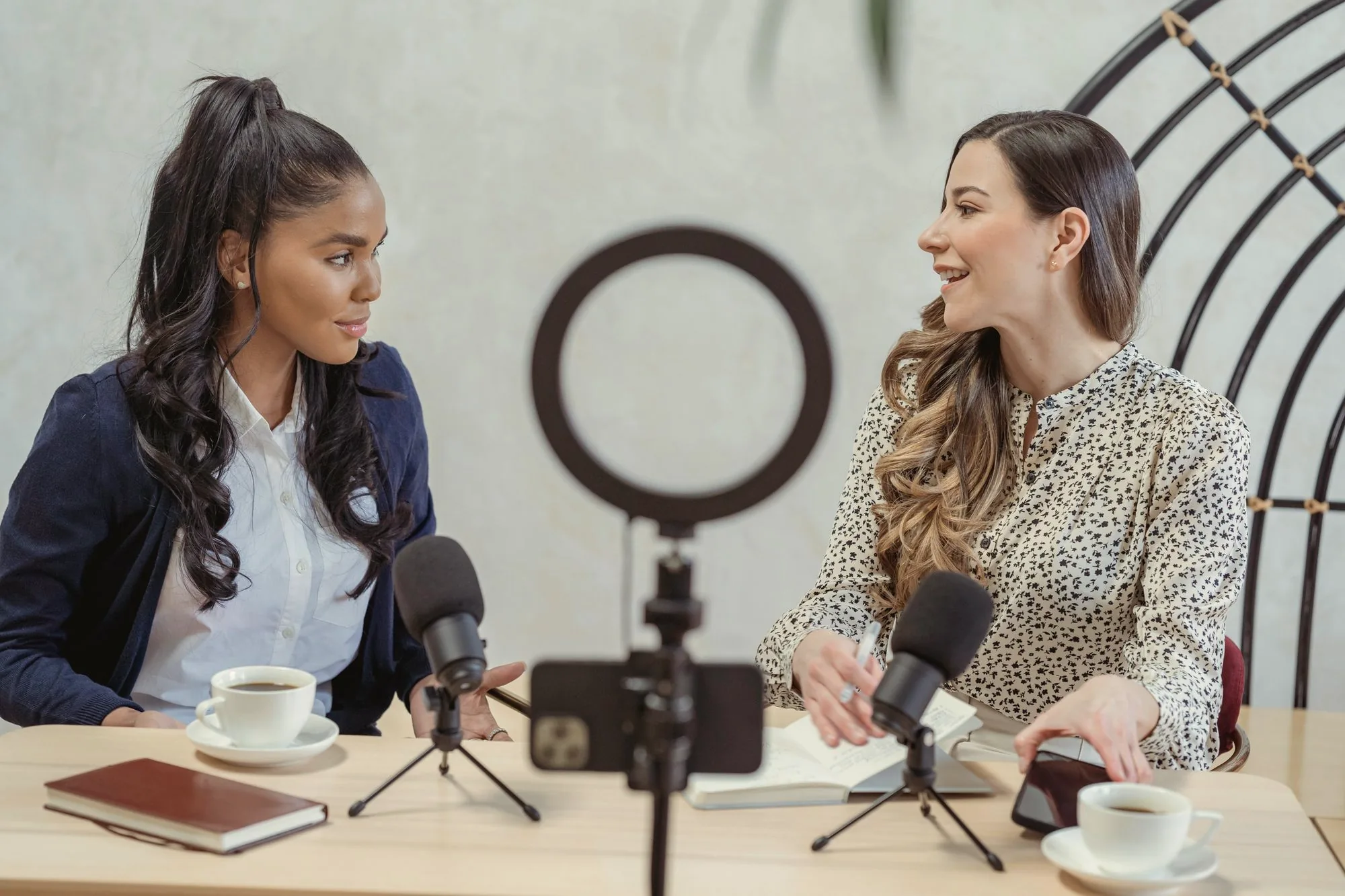 Two women recording a video podcast interview with microphones