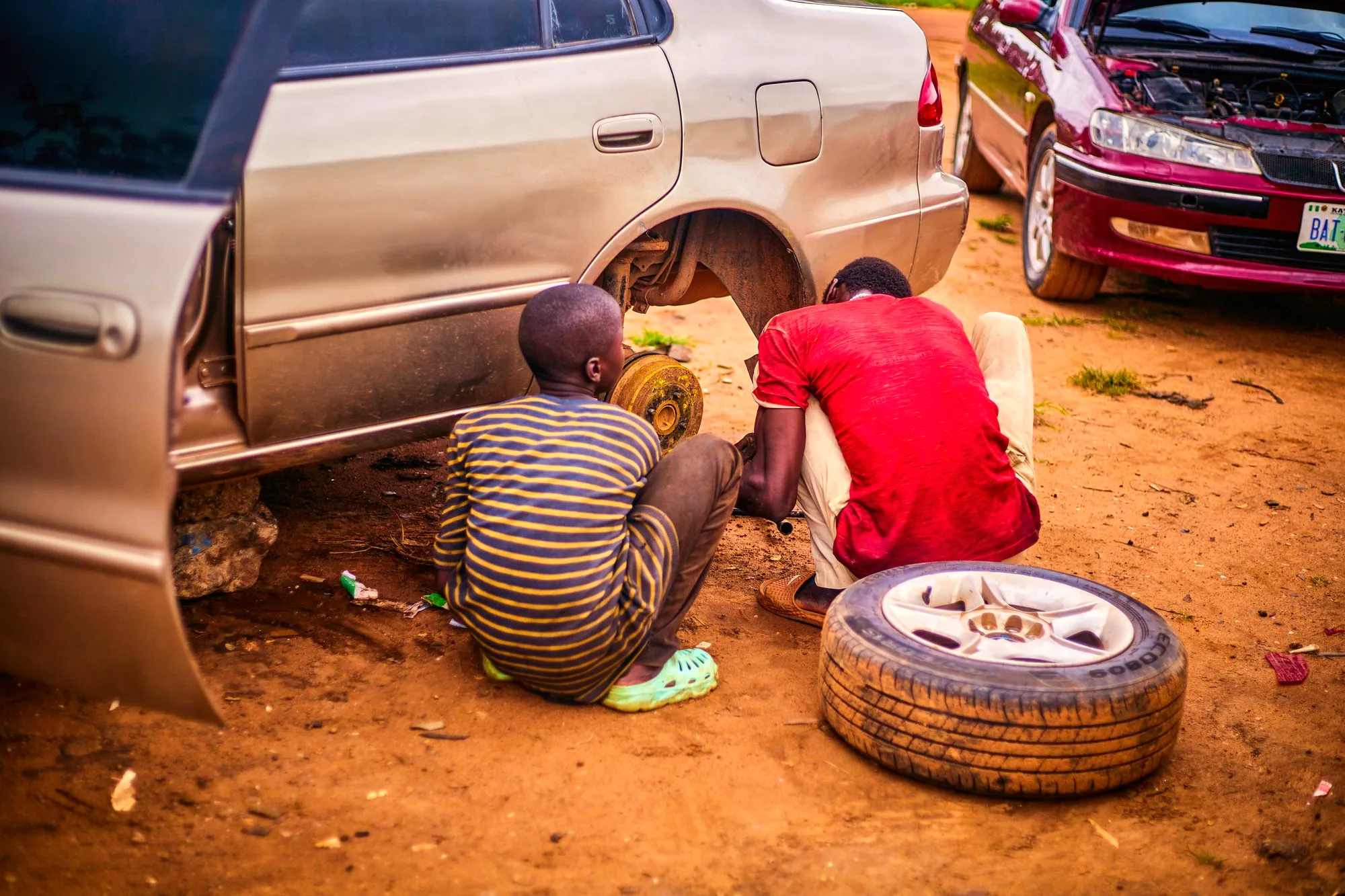 Two mechanics changing a tyre on a dirt road
